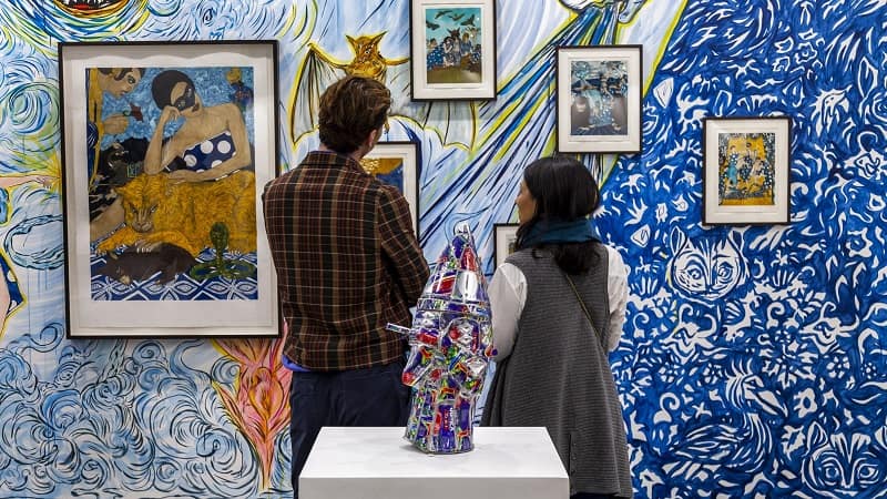  two person are looking at the paintings at India Art Fair – New Delhi, India